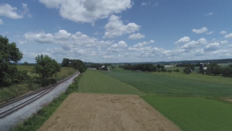 Luftaufnahme-Von-Ackerland-Und-Landschaft-Mit-Einer-Bahnstrecke-An-Einem-Schönen-Sonnigen-Sommertag