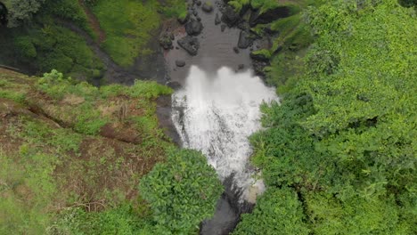Aerial-birds-eye-view-shot-tracking-sipi-river-as-it-falls-over-the-edge-of-a-large-cliff-into-a-green-valley