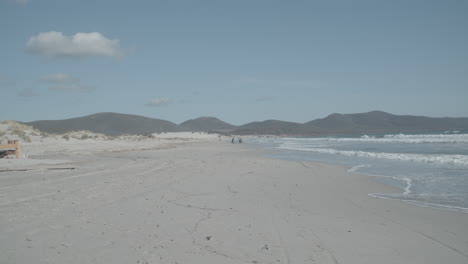 Statische-Aufnahme-Eines-Strandes-Mit-Bergen-Und-Menschen-Im-Hintergrund