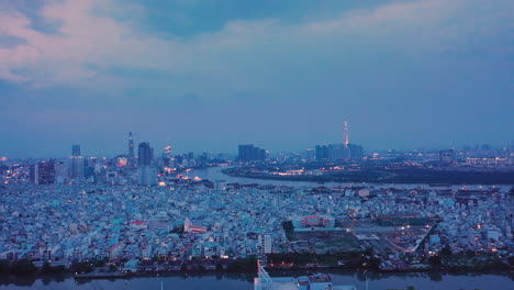 Espectacular-Panorama-Aéreo-Nocturno-De-La-Ciudad-De-Ho-Chi-Minh,-Vietnam-Brillando-Bajo-Las-Luces-Y-Reflejos-En-El-Río-Saigón