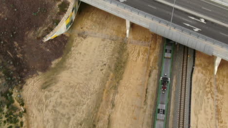 Drone-tracks-above-Perth-Train-driving-under-bridge-on-Joondalup-to-Butler-Line