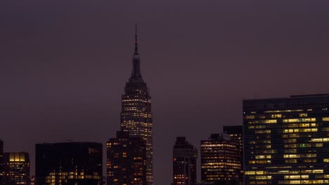 Time-Lapse-of-Empire-State-Building-while-the-sun-goes-down-in-Manhattan,-New-York-City,-with-the-United-Nations-Headquarter-in-the-foreground