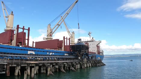Zoom-in-of-cargo-ship-unloading-at-sugar-factory-time-lapse-as-cranes-work-to-move-shipment