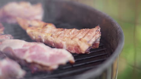 Slow-Motion-of-Tongs-Flipping-Sizzling-Meat-on-Fiery-and-Smokey-BBQ-Grill