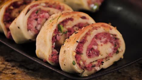 Homemade-Pepperoni-Roll-Italian-Stromboli-sliced-and-displayed-in-a-black-plate,-slider-motion-close-up