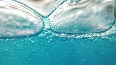Makroansicht-Von-Seifenblasen-In-Blauer-Flüssigkeit,-Die-Sich-Bewegt-Und-Wächst
