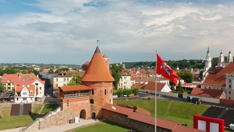 Aerial-shot-going-up-focused-in-the-main-tower-and-a-red-flag-of-Kaunas-castle