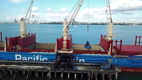 Aerial-Pan-of-cargo-ship-crane-offloading-sugar-in-Chelsea-Sugar-Factory,-Auckland-harbor,-New-Zealand-4k
