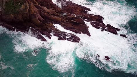 Blue-Ocean-Waves-Break-on-Jagged-Rocks-in-Big-Sur-Cali,-Drone-Reveal