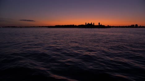 wide-shot,-from-a-boat,-showing-sailing-ship,-statue-of-liberty-at-dusk,-teal-and-orange-sky