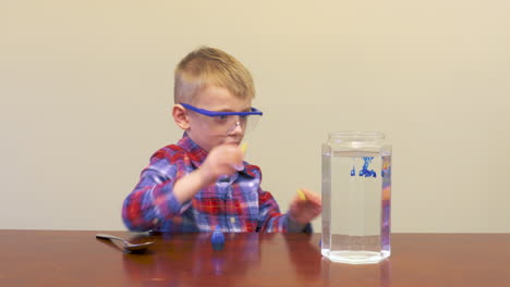 Niño-Pequeño-Con-Gafas-De-Seguridad-Mezclando-Colores-Para-Un-Experimento-Científico
