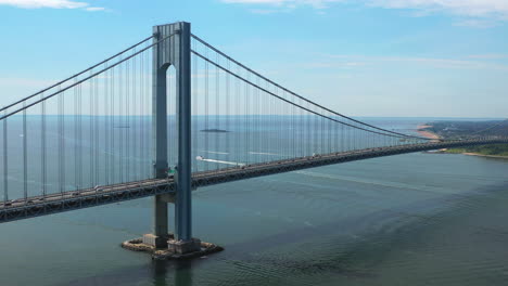 Aerial-view-of-the-Verrazano-Bridge-as-the-drone-camera-pans-right-viewing-Staten-Island-and-the-waters-below-on-a-sunny-morning,-orbit-2