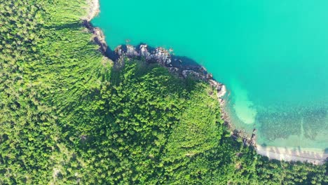 Felsküste-Der-Tropischen-Insel-Mit-Dichtem-Baumwald-Und-üppiger-Vegetation,-Die-Von-Einer-Ruhigen-Türkisfarbenen-Lagune-Mit-Korallenriffen-Unter-Wasser-In-Thailand-Umspült-Wird