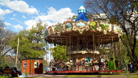 Children-riding-horses-on-spinning-vintage-carousel-in-a-park