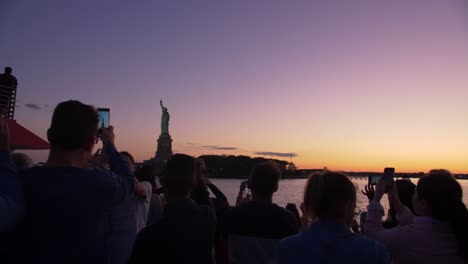 tourists-taking-pictures-of-statue-of-liberty-from-a-boat-at-dusk