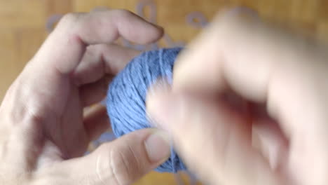 Close-up-of-hand-winding-ball-of-blue-wool