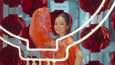 Beautiful-Asian-woman-wearing-traditional-red,-sleeveless-dress-poses-by-the-paper-lanterns-as-she-celebrates-the-Chinese-New-Year---static-slow-motion