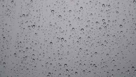 Regentropfen-Auf-Verschwommenem-Grauem-Glasfenster---Regnerische-Tagelemente---Nahaufnahme