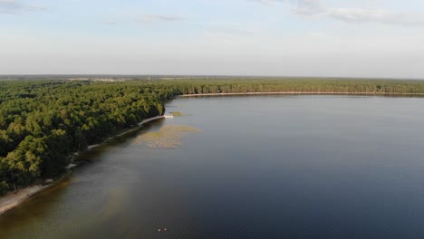 Aerial-View-of-a-Lake-During-a-Summer-Evening-With-Dense-Forest-in-Background