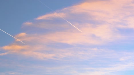 Two-planes-flying-in-parallel-cross-orange-clouds-in-a-blue-sky-during-sunset,-inspiration-for-travelers-and-agencies