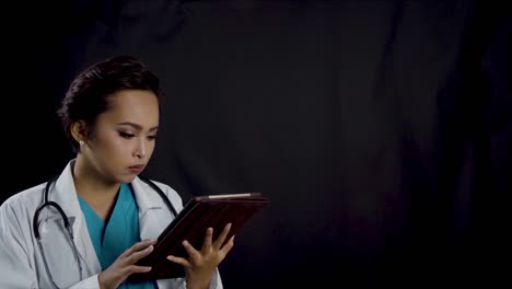 Female-doctor-or-nurse-looks-at-her-tablet-to-see-an-EKG-or-electrocardiogram-readout-which-is-also-animated-in-the-background---copy-space