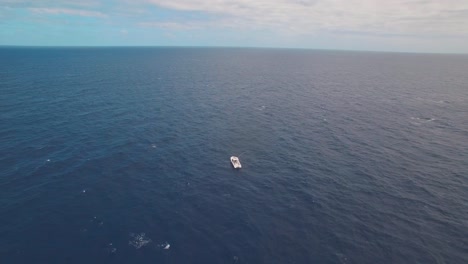 Solitary-Boat-in-the-Middle-of-Blue-Ocean-and-Endless-Horizon,-High-Rise-Pull-Back-Cinematic-Aerial
