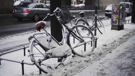 Paar-Fahrräder-Mit-Schnee-Bedeckt-Links-Auf-Der-Straße-An-Stangen-Am-Straßenrand-Gebunden