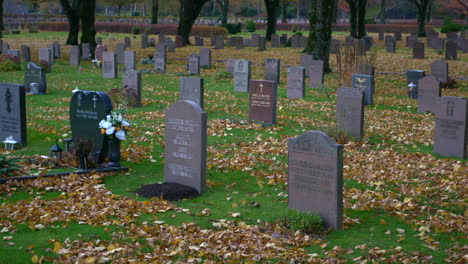 A-beautiful-graveyard-on-an-autumn-day-in-Kviberg-Cemetery-in-Gothenburg,-Sweden---panning-shot