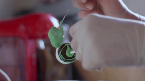 Woman-decorating-a-cake-pop-with-green-coloured-melted-chocolate