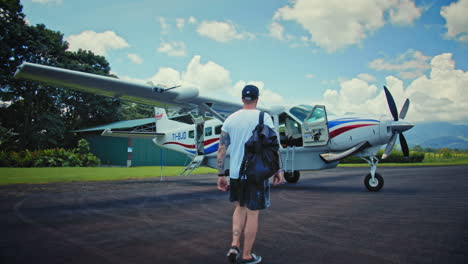 4K-Slow-Motion-Back-shot-of-Traveller-with-Hat-and-Backpack-Waking-Confident-toward-Charter-Plane-at-the-Airfield