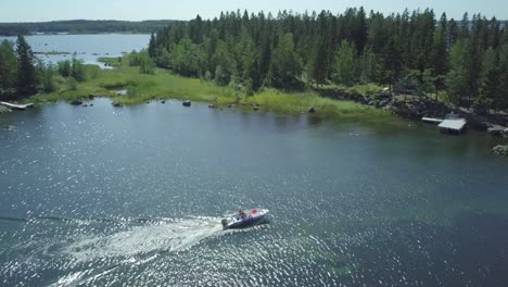 Aerial-of-boat-navigating-through-shallow-water-lake-in-rocky-archipelago