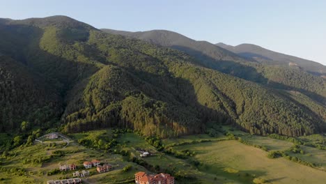 Vista-Aérea-De-Las-Montañas-Pirin-Y-Enormes-Colinas-Cerca-De-Casas-Pequeñas