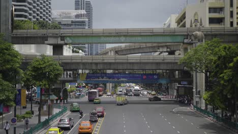 BTS-Skytrain-moving-over-busy-road-in-Bangkok-city-center,-fast-motion