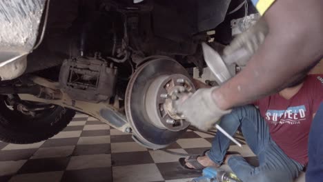 Mechanics-working-on-a-car's-axle-trying-to-fix-it