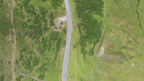 Aerial-top-down-view-of-a-country-road-with-a-car-parked-at-the-side,-bright-sunny-day