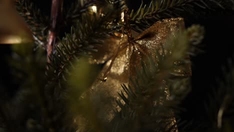 Christmas-tree-decor-leaves-with-jingle-bells-hanging,-closeup-sliding-shot