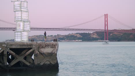 Guy-takes-pictures-of-view-at-25th-April-Bridge-in-Lisbon,-Portugal