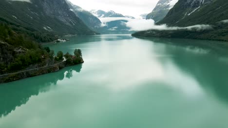 Turquoise-lake-waters-flowing-past-under-drone-flying-at-Loen,-western-Norway