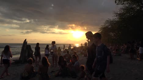 Große-Gruppensilhouette-Menschen-Versammelten-Sich-Am-Sonnenuntergang-Glühenden-Sandstrand-Küstenlinie-Beobachten-Ozean