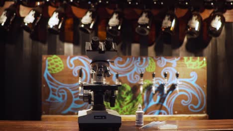 A-Microscope-At-The-Bar-Counter-With-Growlers-And-Draft-Beer-Taps-In-The-Background---zoom-out-slowmo-shot