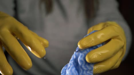 Hands-wringing-out-cleaning-cloth-wearing-yellow-rubber-gloves-close-up-shot