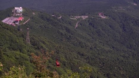 Red-Cable-Car-At-Tsukuba-Ropeway-Moving-Down-The-Lush-Mountain-In-Ibaraki,-Japan---high-angle-shot