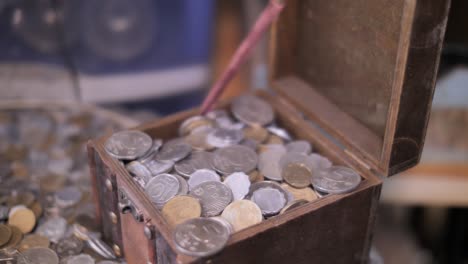 Finger-opening-treasure-chest-with-coins-close-up