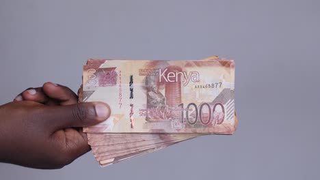 Close-up-shot-of-hands-revealing-Kenyan-shilling-currency-money-cash-from-the-left