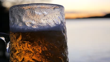 Mientras-El-Sol-Se-Pone-En-El-Archipiélago-Sueco,-Se-Vierte-Una-Cerveza-Lager-Fría-En-Un-Vaso-De-Cerveza-Ondulado