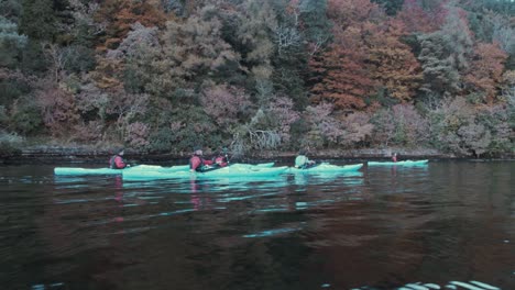 Kayakers-paddling-beside-Autumn-colored-shoreline