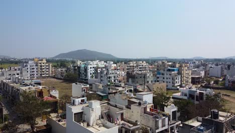 Aerial-view-of-small-city-overtaking-village-in-Indore,-India-I-Combination-of-small-city-and-village-with-beautiful-mountain-in-the-background