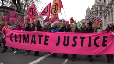 People-lead-an-Extinction-Rebellion-protest-with-a-large-bright-pink-banner-that-says-“Climate-Justice”