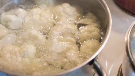 Cauliflower-boils-in-a-metal-pot-over-a-white-covered-stove