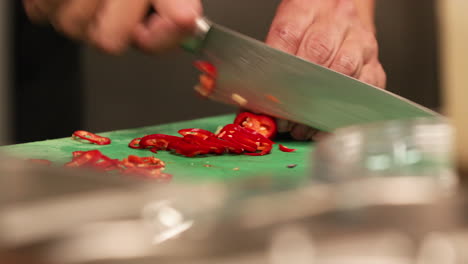 Chef-Cortando-Chiles-Rojos-En-Una-Tabla-De-Cortar-Usando-Un-Cuchillo-En-La-Cocina-De-Un-Restaurante